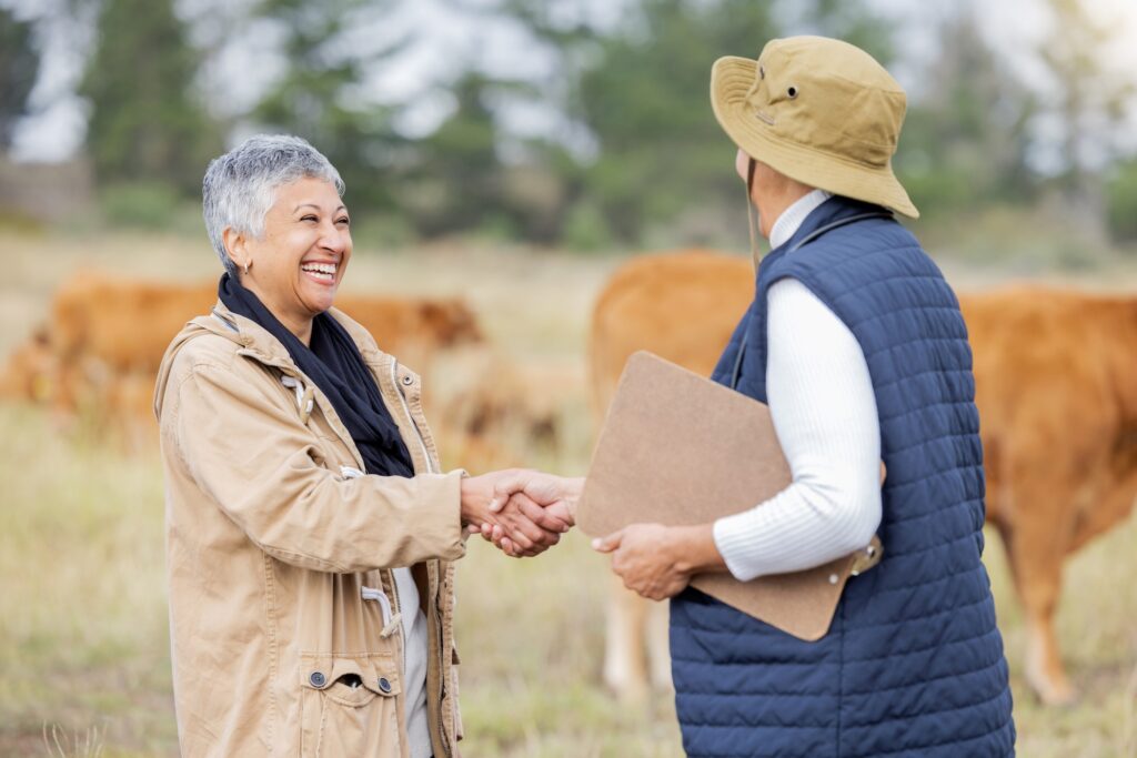 A farmer and lender shake hands outdoors after discussing ag financing for mortgage brokers