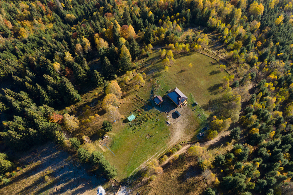 Aerial view of a small countryside homestead and colorful autumn forest, obtained through an agriculture land loan.